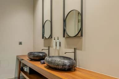 Junior Suite bathroom with two stone vessel basins on a wooden vanity and two round mirrors