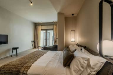 Junior Suite double bed under oval pendant lamps, the room leading to a curtained glass door