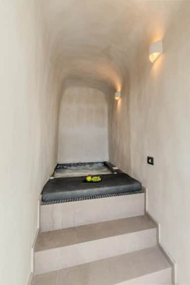 Junior Suite Jacuzzi in a vaulted cave-style alcove, reached by stone steps, with fruit on the cushioned edge
