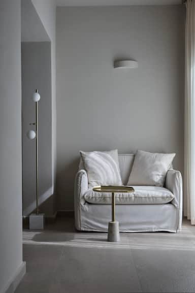 Superior Double Room seating corner with a white slipcovered loveseat, a brass side table and a two-globe floor lamp