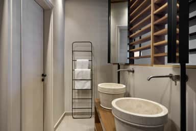 Vanity with twin stone basins, wall taps and a towel ladder