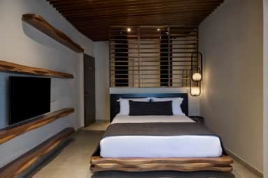 Bedroom with a platform bed, live-edge wooden shelves and a wall TV