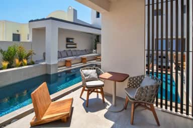 Poolside terrace of the Superior Double by the Pool with two woven chairs, a small table and a wooden lounger