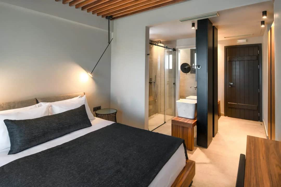 Superior Double Room with a double bed, a glass walk-in shower and a white basin by the dark wooden door