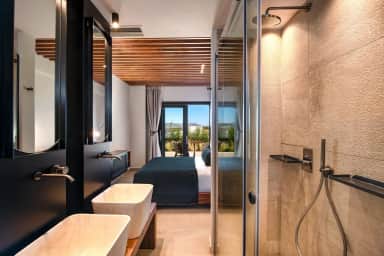 Rain shower and twin basins in the bathroom, looking through to the bed and glass doors to the terrace